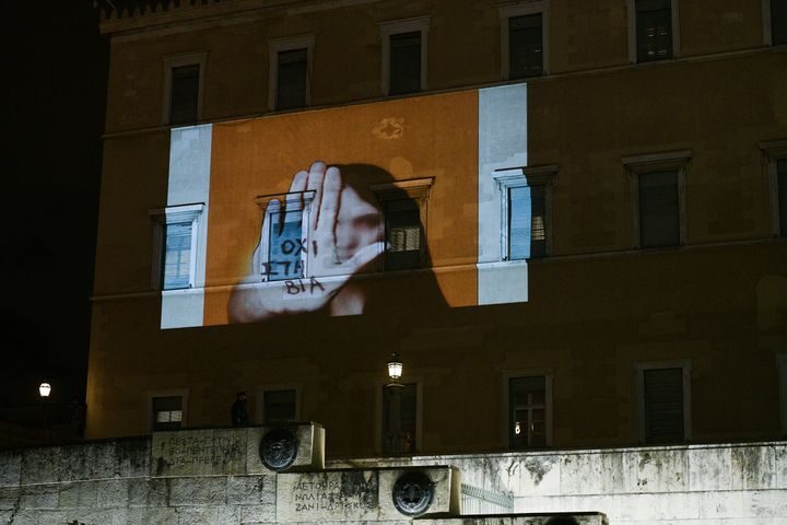 View of the wall of the Hellenic Parliament with a girl writing on her hand "no to violence"