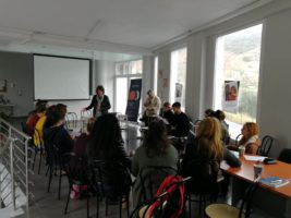 στιγμιότυπο από την επιμόρφωση, συμμετέχουσες/οντες κάθονται περιμετρικά μιας φωνεινής αίθουσας, η εισηγήτρια βρίσκεται όρθια στο κέντρο