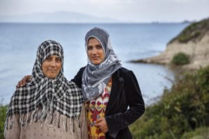 Φωτογραφία. Δύο προσφύγισσες κοιτούν τον φακό με φόντο τη θάλασσα