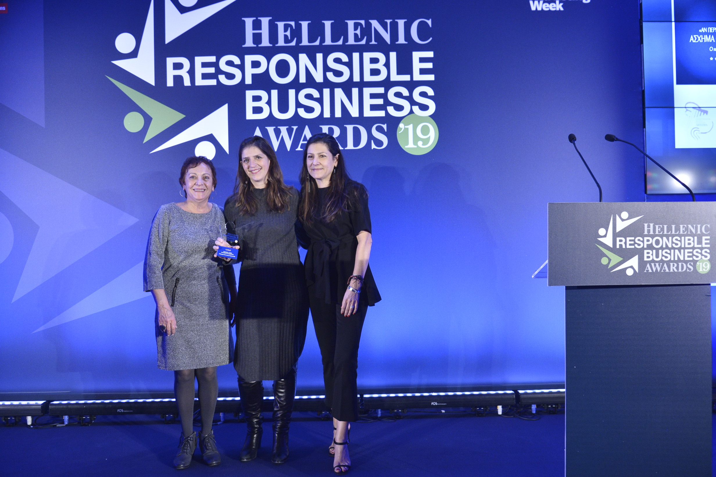 three women are photographed on stage after the award ceremony