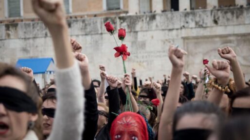 Γυναικεία χέρια με λουλούδια υψωμένα μπροστά στην Βουλή των Ελλήνων