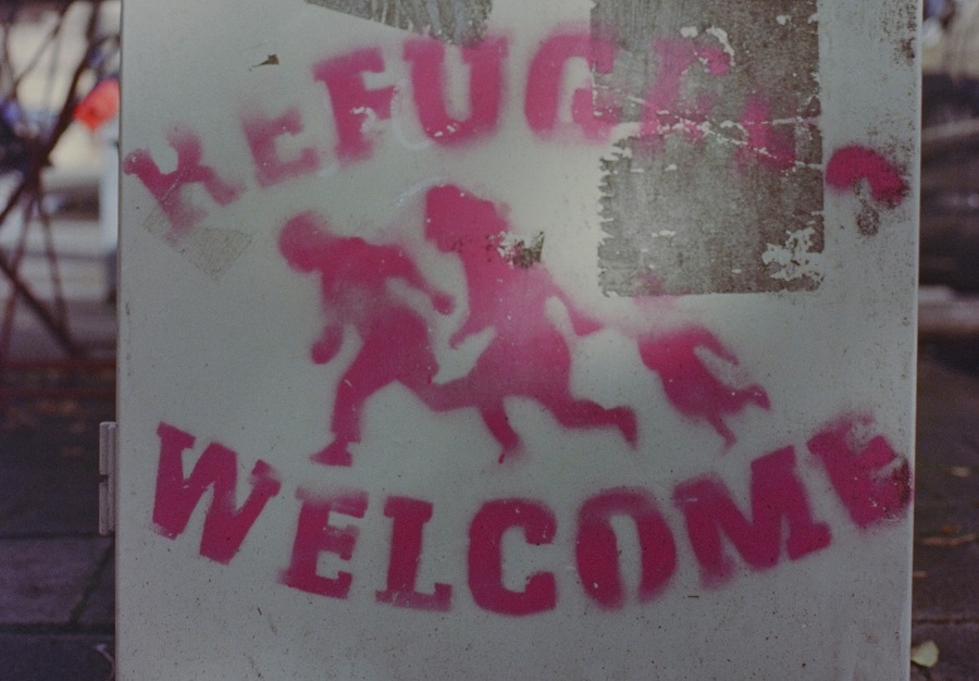 Graffiti που λέει "Refugees welcome" με ροζ γράμματα