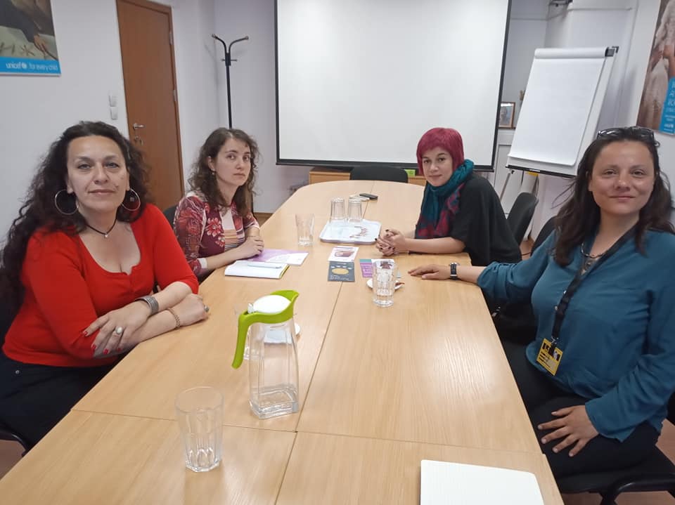 4 women around a long work table smile at the camera