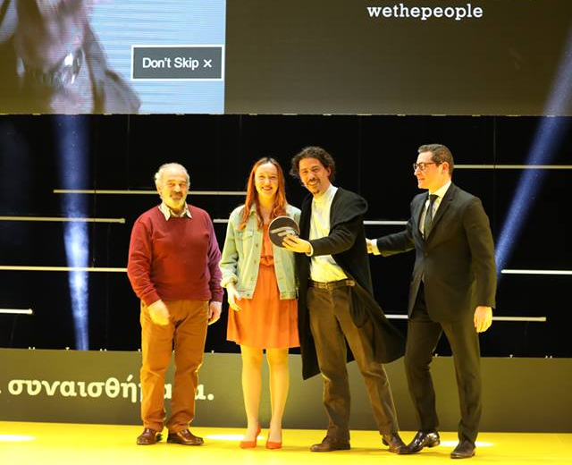 three men and one woman standing on stage after winning an award