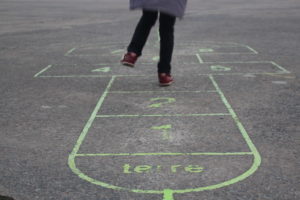ένα παιδί παίζει το «κουτσό» στο δρόμο