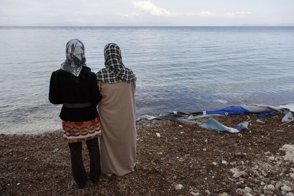 two refugee women on the shore looking at the sea