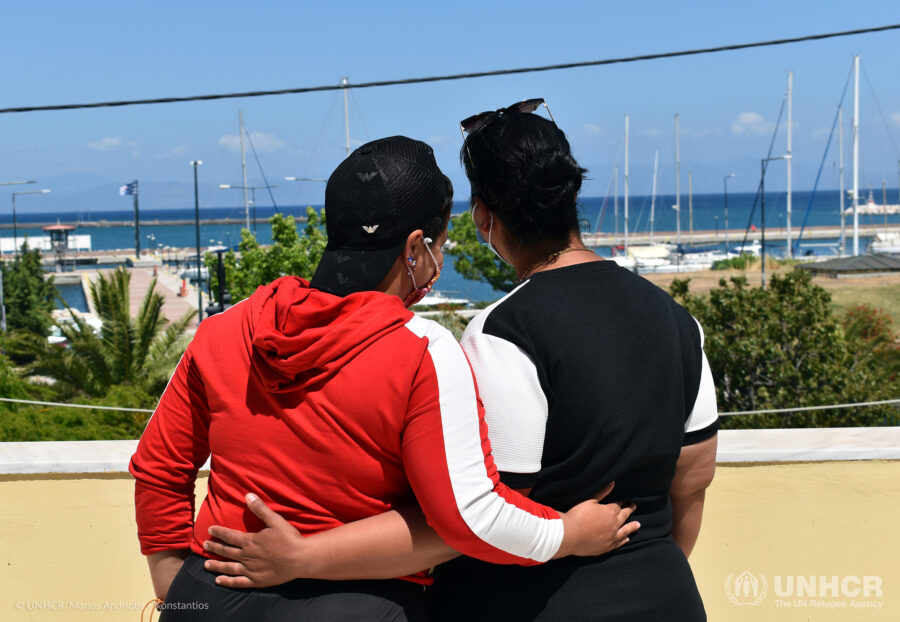 two women hugging and looking towards the sea, we only see their backs