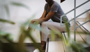 Photo. A woman of colour is sitting in the stairs.