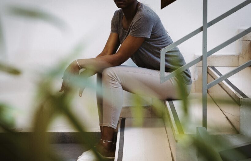 Photo. A woman of colour is sitting in the stairs.