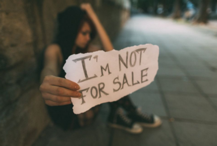 a woman holds a piece of paper that reads «I'm not for sale»
