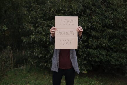 a woman holds a sign that reads « Love shouldn't hurt»