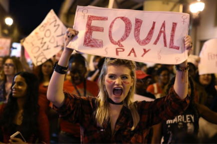 a woman holds a sign that reads «equal pay»