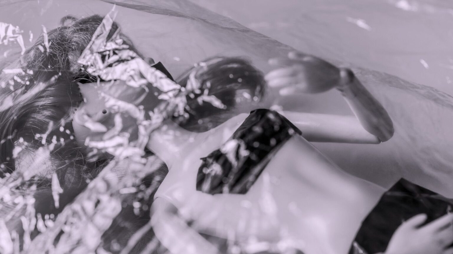 μια κούκλα βιτρίνας πεσμένη στο πάτωμα και τυλιγμένη με σελοφάν