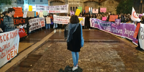 στιγμιότυπο από φεμινιστική διαμαρτυρία, τα πανό είναι παρατεταγμένα σε σχήμα «π» στη μέση στέκεται μία γυναίκα