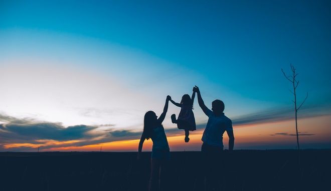 μια γυναίκα και ένας άνδρας κρατούν ανάμεσα τους ένα κοριστάκι και το σηκώνουν ψηλά