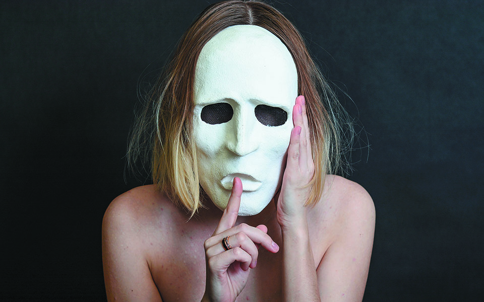 μια ξανθιά γυναίκα πίσω από μια λευκή μάσκα θεάτρου