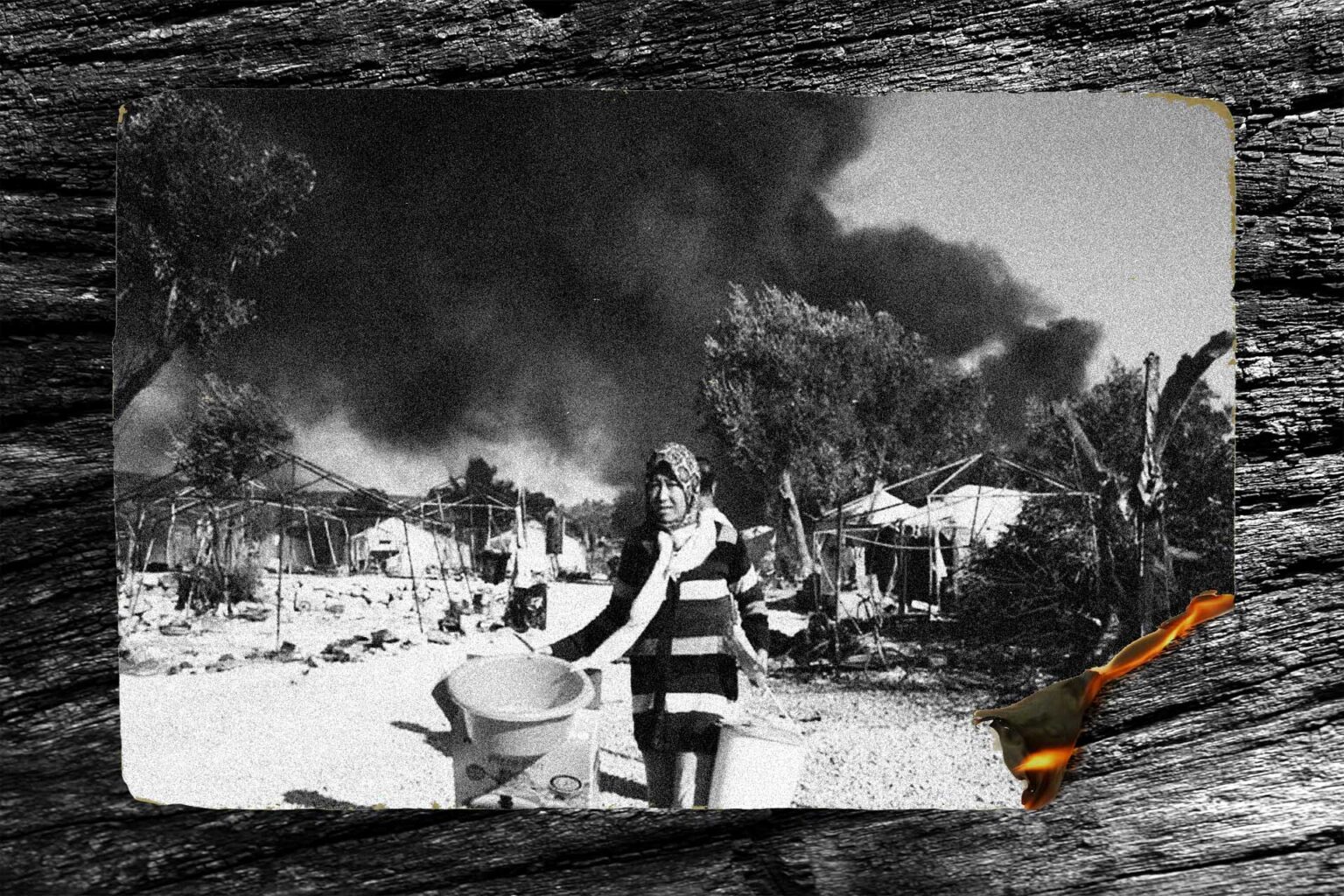 ασπρόμαυρη φωτογραφία, μια γυναίκα με μαντίλα τρέχει με πράγματα στα χέρια, πίσω της διακρίνονται μεγάλοι μαύροι καπνοί