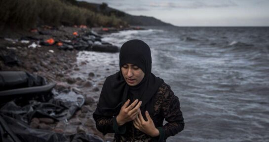 προσφύγισσα απομακρύνεται από ένα ναυάγιο με τα χέρια σταυρομένα στο στήθος