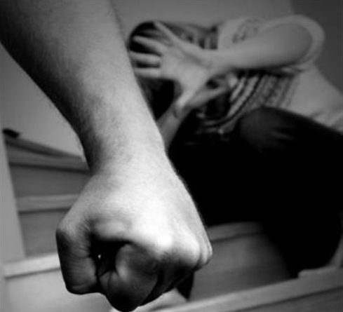 η σφιγμένη γροθιά ενός άνδρα και στο φόντο μια γυναίκα που κρύβεται πίση από την ανοιχτή της παλάμη