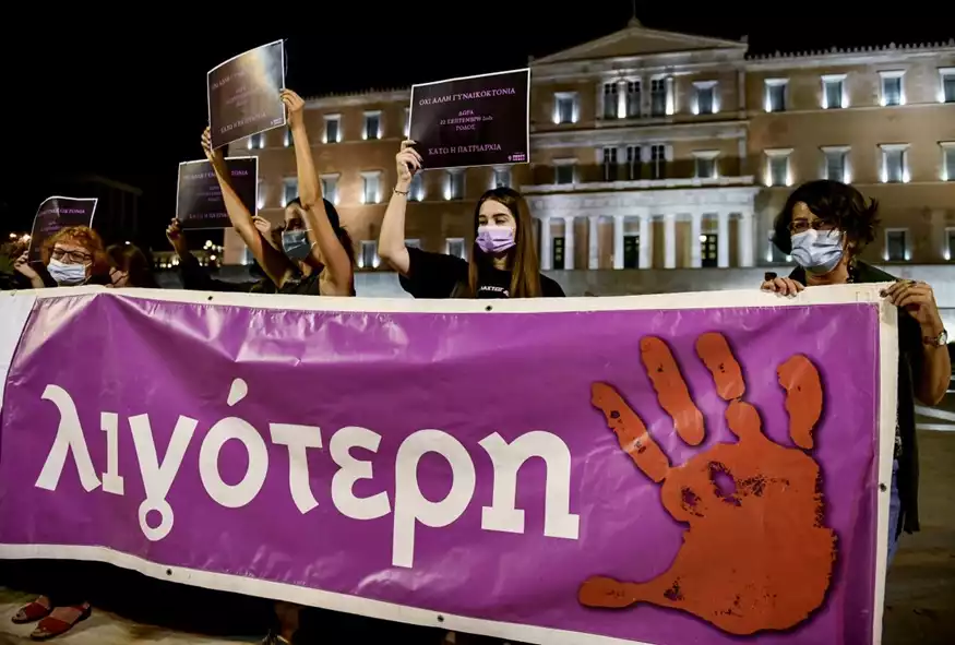 γυναίκες κρατούν ένα πανό μπροστά από τη Βουλή των Ελλήνων, το οποίο γράφει «Καμία Ελένη λιγότερη»