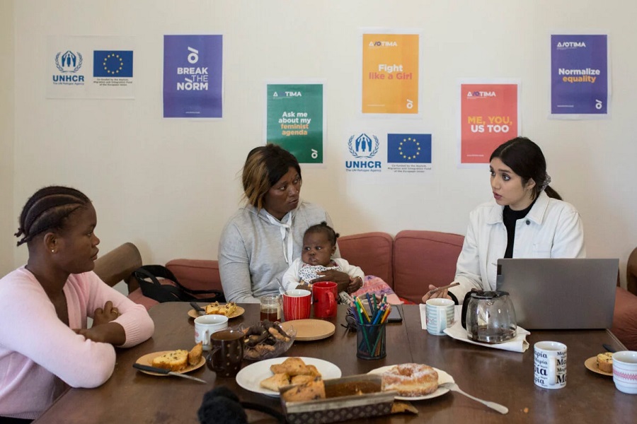 Women discussing around a table. Colourful posters on the wall.