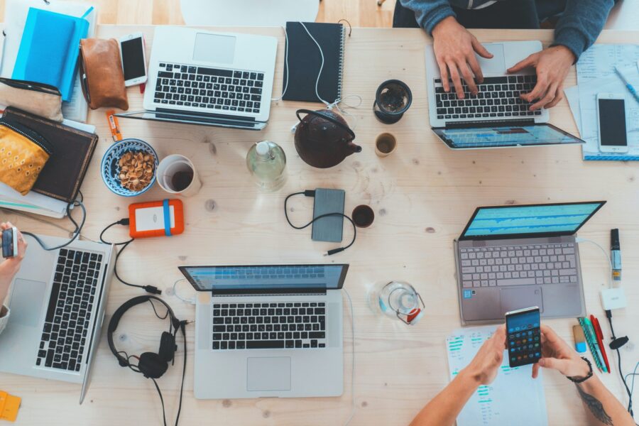 Photo of a table, There are laptops, headphones, smartphones and notepads around.