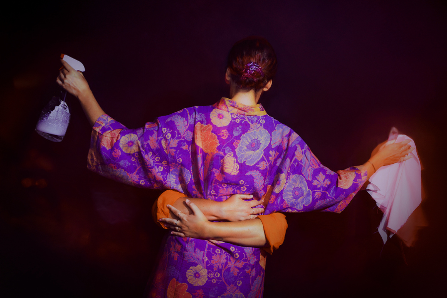 CAREFULL | Παράσταση «θεάτρου forum», εικόνα με γυναίκα πλάτη που φοράει κιμονό και κρατά ένα ξεσκονόπανο και ένα άζαξ