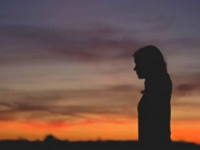 μια γυναίκα προφίλ και στο βάθος τα χρώματα του δειλινού