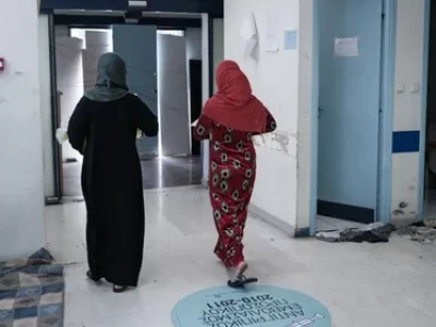 δύο προσφύγισσες περπατούν σε εσωτερικό χώρο δομής φιλοξενίας