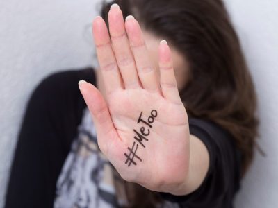 μια γυναίκα κρύβεται πίσω από την παλάμη της, η οποία γράφει «#metoo