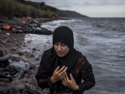 προσφύγισσα απομακρύνεται από ένα ναυάγιο με τα χέρια σταυρομένα στο στήθος