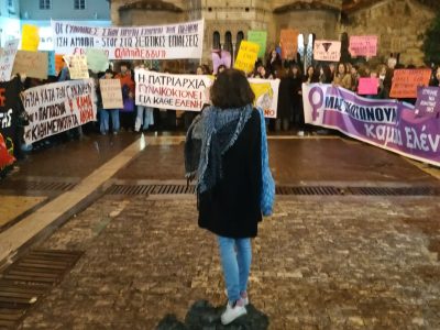 στιγμιότυπο από φεμινιστική διαμαρτυρία, τα πανό είναι παρατεταγμένα σε σχήμα «π» στη μέση στέκεται μία γυναίκα