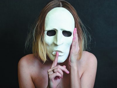 μια ξανθιά γυναίκα πίσω από μια λευκή μάσκα θεάτρου