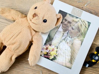 μια φωτογραφία γάμου πίσω από μια σπασμένη κορνίζα και δύο παιδικά παιχνίδια