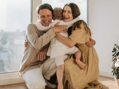 ένα ανδρόγυνο αγκαλιάζει σφιχτά ένα παιδί