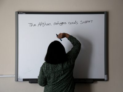 «Οι Αφγανές προσφύγισσες χρειάζονται υποστήριξη» γράφει μία γυναίκα στον πίνακα